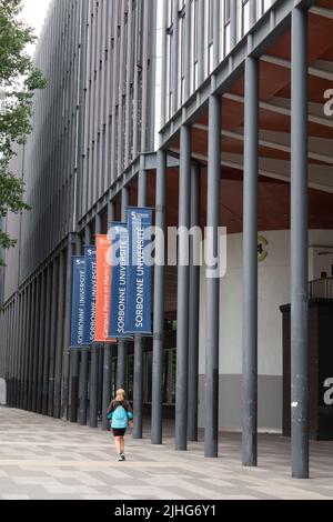 Una persona che cammina accanto alla parte moderna dell'Università della Sorbona con bandiere sulla costruzione di Parigi Francia Foto Stock