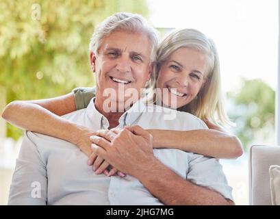 Una coppia caucasica matura felice che abbraccia e mostra l'amore mentre si rilassa insieme a casa. Pensionato coppia legame mentre seduto insieme Foto Stock