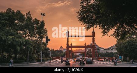 Guilin, Cina - Agosto 2019 : traffico di auto e scooter in tarda serata sul ponte Rosso sul fiume li in via Sanduo Lu al tramonto, provincia di Guangxi Foto Stock