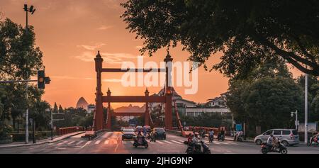 Guilin, Cina - Agosto 2019 : traffico di auto e scooter in tarda serata sul ponte Rosso sul fiume li in via Sanduo Lu al tramonto, provincia di Guangxi Foto Stock