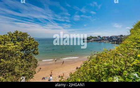 Tenby, Galles - Maggio 2021 : persone che godono di sole giorno caldo sulla storica spiaggia e costa della città di Tenby, Carmarthen Bay, Pembrokeshire Foto Stock