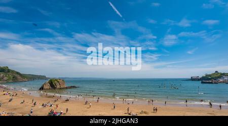 Tenby, Galles - Maggio 2021 : persone che godono di sole giorno caldo sulla storica spiaggia e costa della città di Tenby, Carmarthen Bay, Pembrokeshire Foto Stock