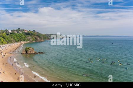 Tenby, Galles - Maggio 2021 : persone che godono di sole giorno caldo sulla storica spiaggia e costa della città di Tenby, Carmarthen Bay, Pembrokeshire Foto Stock