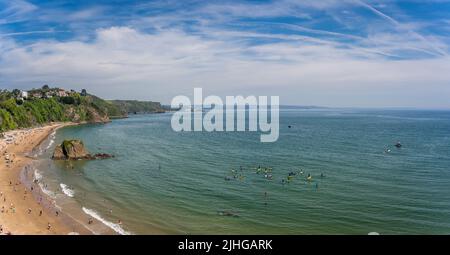 Tenby, Galles - Maggio 2021 : persone che godono di sole giorno caldo sulla storica spiaggia e costa della città di Tenby, Carmarthen Bay, Pembrokeshire Foto Stock