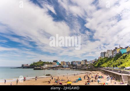 Tenby, Galles - Maggio 2021 : persone che godono di sole giorno caldo sulla storica spiaggia e costa della città di Tenby, Carmarthen Bay, Pembrokeshire Foto Stock