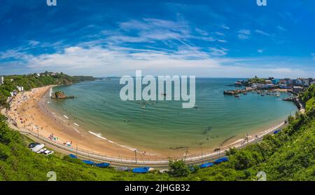 Tenby, Galles - Maggio 2021 : persone che godono di sole giorno caldo sulla storica spiaggia e costa della città di Tenby, Carmarthen Bay, Pembrokeshire Foto Stock