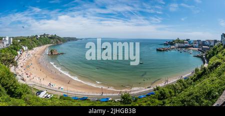 Tenby, Galles - Maggio 2021 : persone che godono di sole giorno caldo sulla storica spiaggia e costa della città di Tenby, Carmarthen Bay, Pembrokeshire Foto Stock