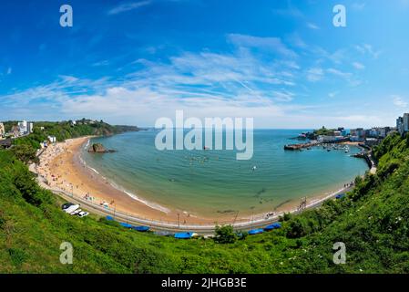 Tenby, Galles - Maggio 2021 : persone che godono di sole giorno caldo sulla storica spiaggia e costa della città di Tenby, Carmarthen Bay, Pembrokeshire Foto Stock