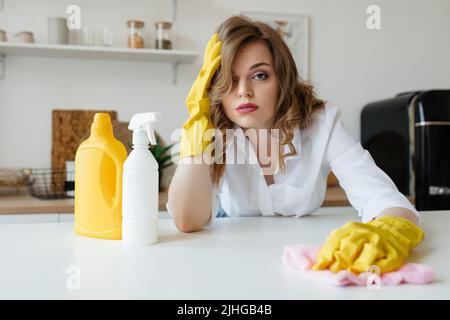 Bella ragazza casalinga sta cercando di asciugare le macchie dal tavolo da cucina Foto Stock