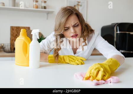 Bella ragazza casalinga sta cercando di asciugare le macchie dal tavolo da cucina Foto Stock