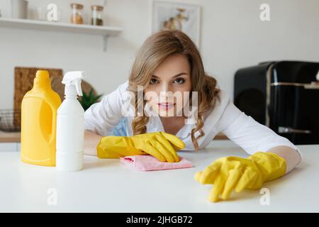 Bella ragazza casalinga sta cercando di asciugare le macchie dal tavolo da cucina Foto Stock