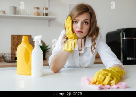 Bella ragazza casalinga sta cercando di asciugare le macchie dal tavolo da cucina Foto Stock