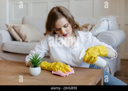 Bella ragazza casalinga sta cercando di asciugare le macchie dal tavolo da cucina Foto Stock