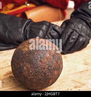 Un gunner in vintage svedese abbigliamento militare e palline di cannone. Antico arsenale militare degli eventi della guerra russo-svedese Foto Stock