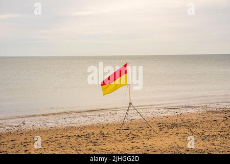 bandiere di avvertimento pericolo rosse e gialle sulla zona di sicurezza delle guardie salvavita della spiaggia Foto Stock