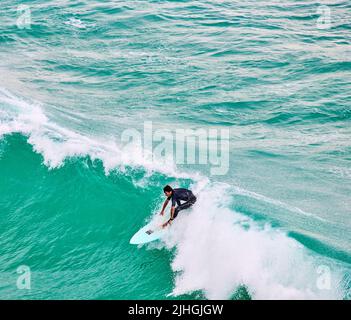 Un surfista corre la cresta di un'onda di surf sull'oceano Atlantico al largo della spiaggia Great Western a Newquay, Cornovaglia, Inghilterra. Foto Stock