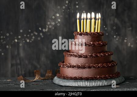 Torta di compleanno al cioccolato a più livelli decorata con glassa al cioccolato e candele di compleanno in oro Foto Stock