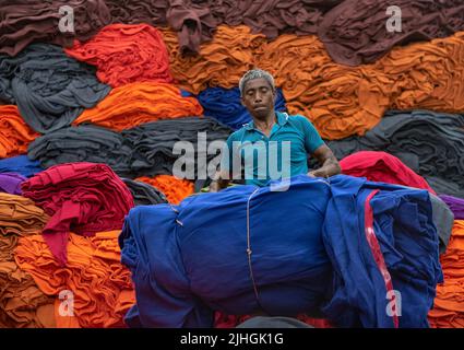 Le coperte colorate vengono caricate sui camion dai lavoratori. Industria tessile in Bangladesh Foto Stock