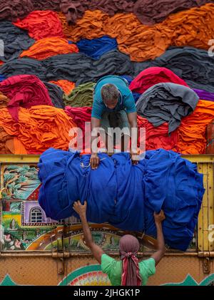 Le coperte colorate vengono caricate sui camion dai lavoratori. Industria tessile in Bangladesh Foto Stock