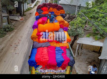 Le coperte colorate vengono caricate sui camion dai lavoratori. Industria tessile in Bangladesh Foto Stock