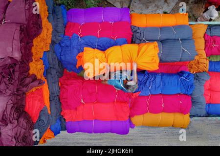 Le coperte colorate vengono caricate sui camion dai lavoratori. Industria tessile in Bangladesh Foto Stock