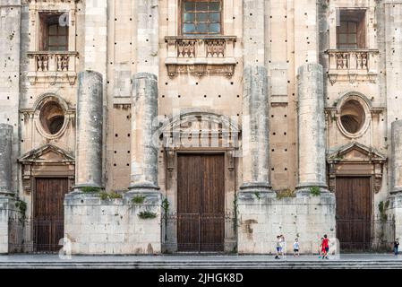 Ragazzi che giocano a calcio sotto la facciata incompiuta dell'enorme chiesa benedettina di San Nicolò l'Arena (iniziata nel 1687), Catania, Sicilia, Italia Foto Stock