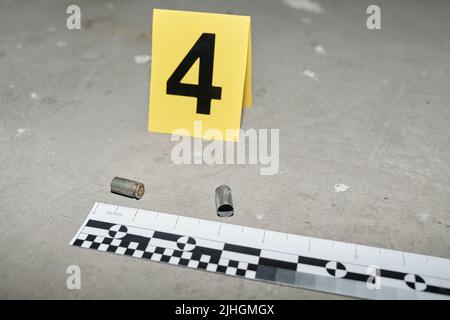 Cartellino giallo con numero quattro in piedi su asfalto da due cassette vuote rimaste sulla scena del crimine sparato da una pistola di assassino Foto Stock