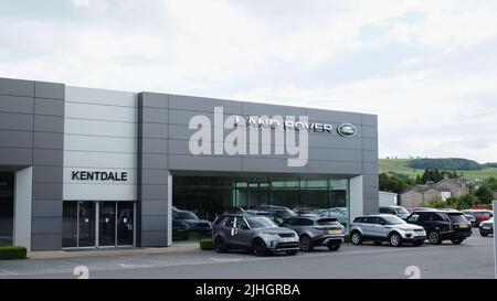 Il garage Jaguar Land Rover di Kentdale con vari Land Rover sul piazzale e il grande edificio moderno della concessionaria dietro il marchio Land Rover Foto Stock