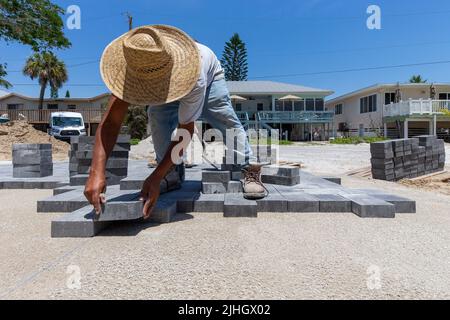 l'asfaltatrice professionale sta posando mattoni di pavimentazione su una superficie sabbiosa preparata per creare un percorso a piedi e un vialetto per una nuova casa in costruzione Foto Stock