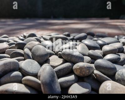 Vista ravvicinata ad angolo basso attraverso le pietre del fiume e le ombre a chiazze sullo sfondo Foto Stock