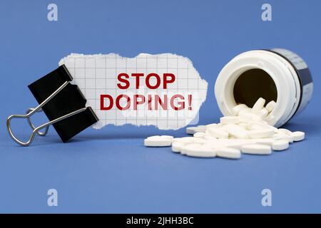 Concetto di medicina. Sulla superficie blu si trova un vaso di pillole e una clip con carta su cui è scritto - Stop doping Foto Stock