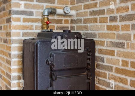 Riscaldamento della casa con legno e carbone. Grande caldaia in ghisa nera per il riscaldamento domestico. La caldaia funziona con combustibile solido. Un'opzione di fallback per il riscaldamento domestico Foto Stock