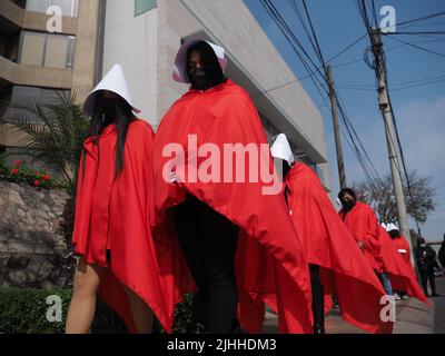 Lima, Perù, 18/07/2022, madri, vittime di violenza domestica o economica, transpersone, migranti, E tutti i tipi di donne e di diversità che indossano il coif bianco e il mantello rosso svolgono la performance di strada 'la racconto di Handsmaid' per attirare l'attenzione di Michelle Bachelet, l'Alto Commissariato delle Nazioni Unite per i diritti umani che si trova a Lima. Foto Stock