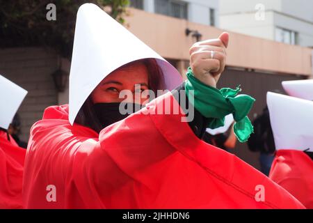 Lima, Perù, 18/07/2022, madri, vittime di violenza domestica o economica, transpersone, migranti, E tutti i tipi di donne e di diversità che indossano il coif bianco e il mantello rosso svolgono la performance di strada 'la racconto di Handsmaid' per attirare l'attenzione di Michelle Bachelet, l'Alto Commissariato delle Nazioni Unite per i diritti umani che si trova a Lima. Foto Stock