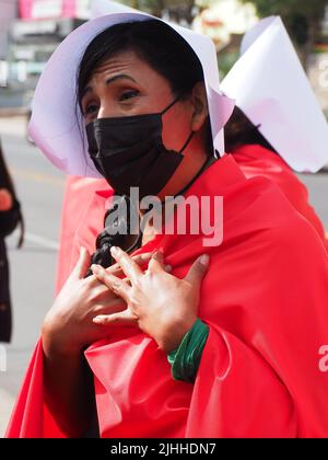 Lima, Perù, 18/07/2022, madri, vittime di violenza domestica o economica, transpersone, migranti, E tutti i tipi di donne e di diversità che indossano il coif bianco e il mantello rosso svolgono la performance di strada 'la racconto di Handsmaid' per attirare l'attenzione di Michelle Bachelet, l'Alto Commissariato delle Nazioni Unite per i diritti umani che si trova a Lima. Foto Stock