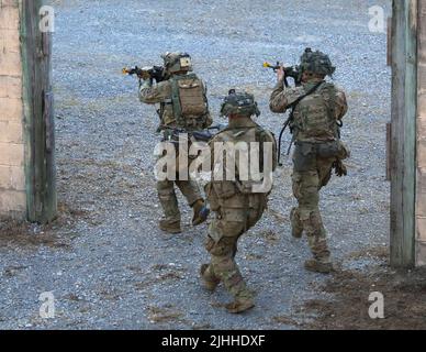 Tre soldati di 2nd Battaglione, 506th Fanteria, 3rd Brigata Combat Team, 101st Airborne Division (Air Assault), avanzano su una posizione nemica durante un'esercitazione di assalto dei cattivi a Fort Campbell, Ky. Luglio 15, 2022. I soldati dovevano liberare diversi edifici dalla forza opposta durante l'esercizio. Foto Stock