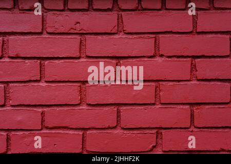 Fotografia di un vecchio muro di mattoni con un fresco cappotto di vernice rossa. Foto Stock