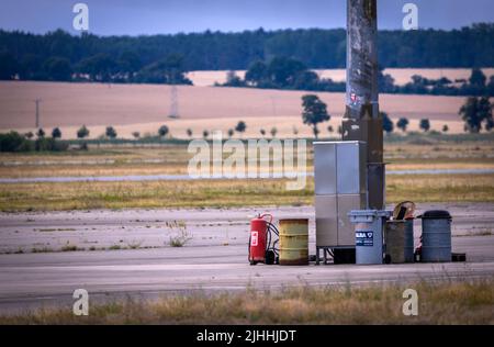 Parchim, Germania. 18th luglio 2022. Un vecchio estintore e barili si trovano sul grembiule dell'ex aeroporto di Parchim-Schwerin. Dopo essere stato acquistato da un investitore cinese, l'ex aeroporto militare dell'esercito russo doveva essere sviluppato in un centro di volo internazionale del carico. Dopo l'insolvenza dell'operatore nel maggio 2019, le operazioni di volo sono cessate e gli impianti all'aperto sono parzialmente sopravallevati. Credit: Jens Büttner/dpa/Alamy Live News Foto Stock