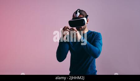 Giovane che gioca a un gioco di boxe in realtà virtuale utilizzando controller di gioco. Giovane videogamer attivo che indossa un visore per la realtà virtuale. un giovane sportivo spiega Foto Stock