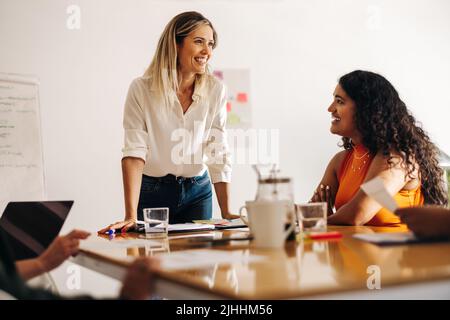 Buone donne d'affari che hanno una discussione durante una riunione in un ufficio creativo. Diverse donne d'affari che condividono idee in una sala riunioni. Gruppo di businesswo Foto Stock