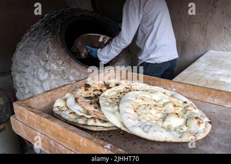 lo chef maschile prepara il pane a forma di cuore. Pane tradizionale arabo che si cuoce su crostini in tandoor. Giordania. Jerash. Grandi tortillas piatte appena sfornate Foto Stock