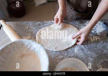 Un panettiere forma e taglia il tradizionale pane francese di Fougasse. Vista frontale. Foto Stock