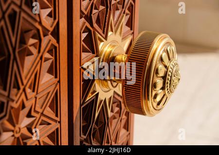 Maniglia per porta rotonda con ornamento. Antica maniglia sullo sfondo di una porta di legno. Foto Stock