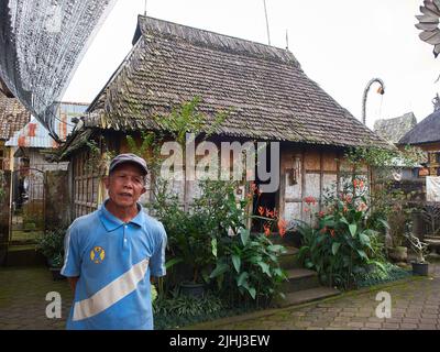 L'uomo Balinese di mezza età racconta una storia sullo sfondo di un'antica casa balinese tradizionale chiamata casa da cucina nel villaggio di Palipuran Foto Stock