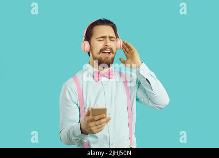 Giovane uomo caucasico positivo ascolta la musica in cuffie con gli occhi chiusi e canta lungo Foto Stock