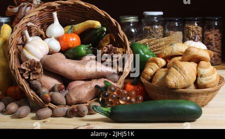 Cestini di verdure fresche e pane in cucina con vasetti di cibo essiccato in background Foto Stock