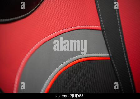 Moderna vettura sportiva con interni in pelle nera e rossa. Parte dei dettagli dei sedili in pelle con cuciture bianche. Foto Stock