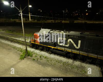 Una locomotiva fissa CN Rail (Canadian National Railway) è visibile di notte con il suo logo illuminato sul lato del treno. Foto Stock