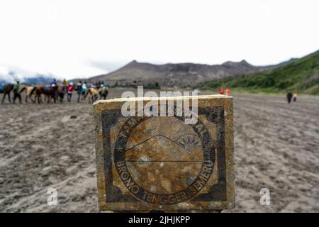 Primo piano di pietra sporca contiene il logo del bromo Tengger Semeru National Park (Taman Nasional) al mattino con sfondo bokeh. Foto Stock