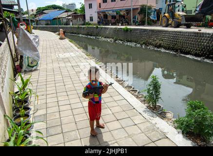 Chiang mai, Tailandia. 18th luglio 2022. Un bambino gioca con un giocattolo pistola al canale Khlong Mae Kha a Chiang mai. Il progetto prevede la costruzione di pavimentazioni, la creazione di un sistema di gestione delle acque reflue e il miglioramento del paesaggio. Il paesaggio urbano lungo sarà una nuova strada pedonale lungo il comune di Chiang mai. Credit: SOPA Images Limited/Alamy Live News Foto Stock